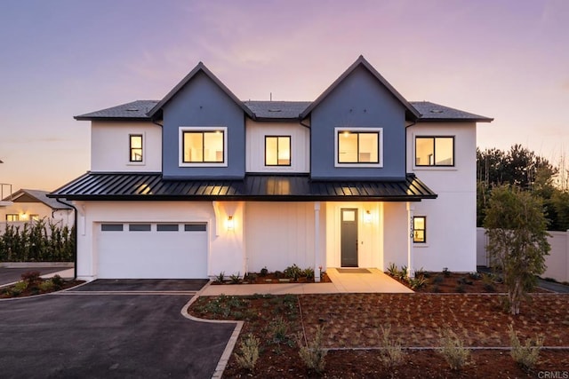 view of front of house featuring a standing seam roof, driveway, an attached garage, and metal roof