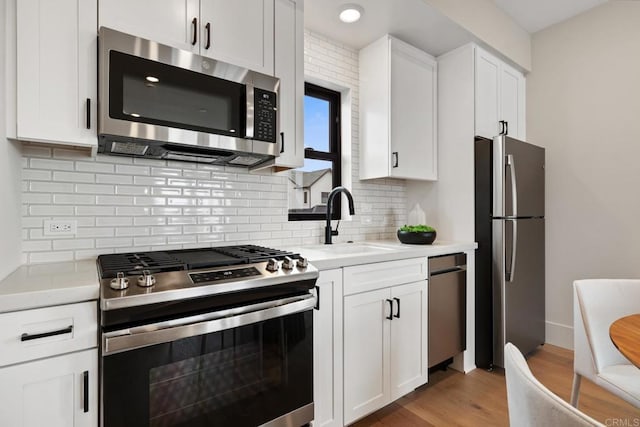 kitchen featuring appliances with stainless steel finishes, light countertops, a sink, and white cabinetry