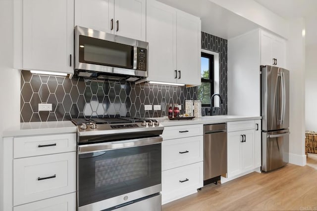 kitchen featuring stainless steel appliances, light countertops, a sink, and white cabinetry