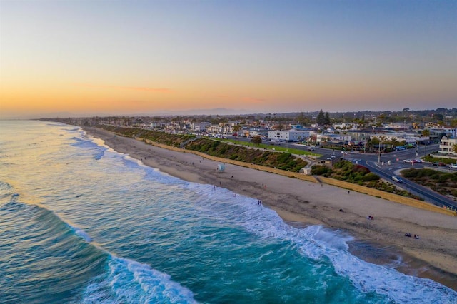 aerial view at dusk with a view of the beach and a water view