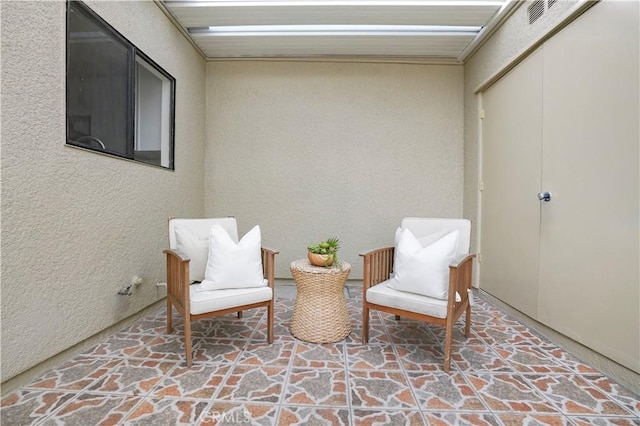 living area with visible vents, stone finish floor, and a textured wall