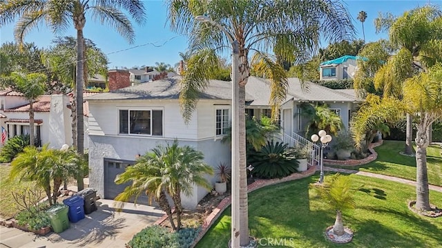 view of front facade featuring driveway, a garage, a chimney, a front yard, and stucco siding