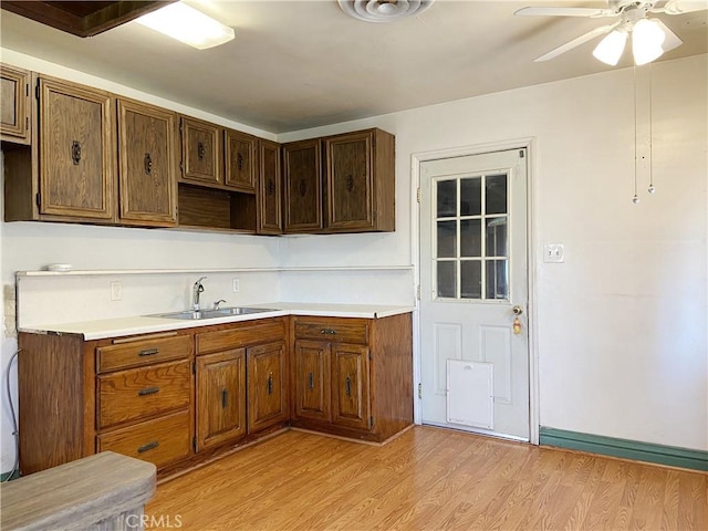 kitchen featuring light wood-type flooring, a ceiling fan, light countertops, and a sink