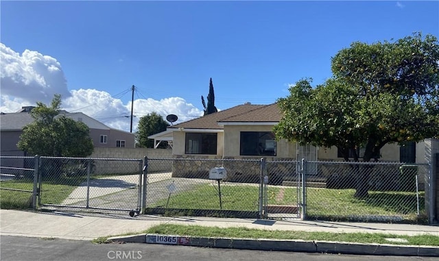 view of front facade with a fenced front yard, a gate, and stucco siding