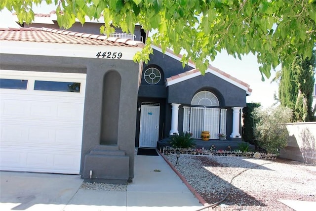 view of front facade with a garage, a tiled roof, and stucco siding