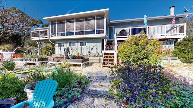 rear view of property featuring a garden, stairway, a wooden deck, and a sunroom