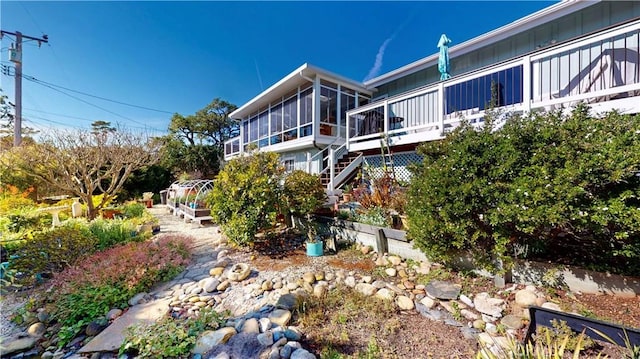 back of property with stairway, board and batten siding, and a sunroom