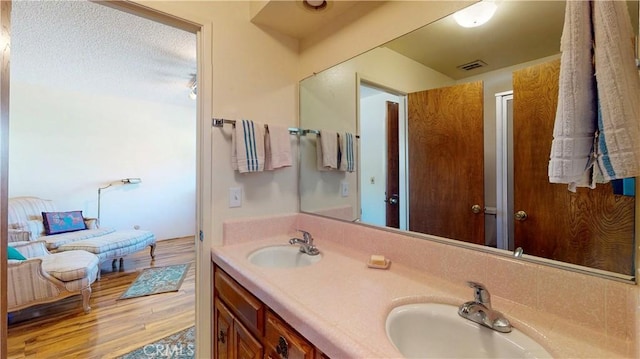 bathroom featuring double vanity, wood finished floors, a sink, and visible vents