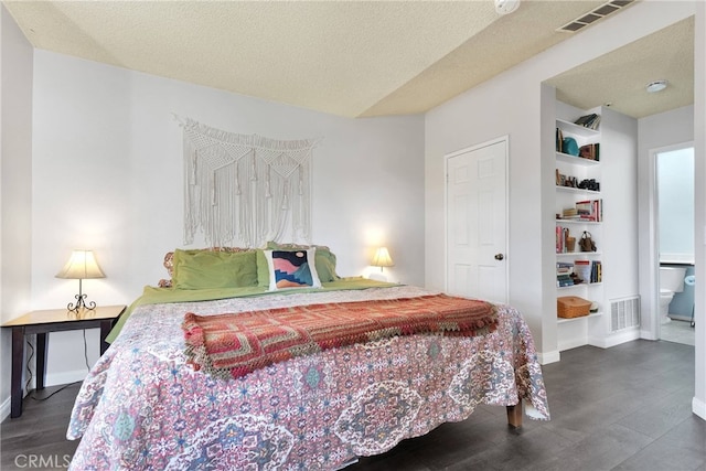 bedroom featuring dark wood-style floors, visible vents, a textured ceiling, and baseboards