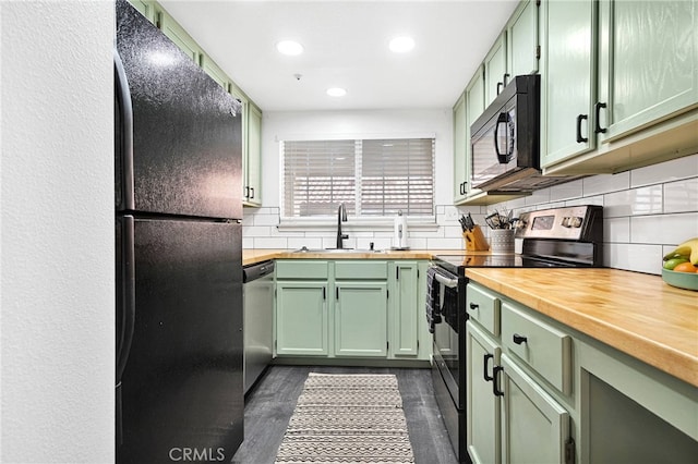 kitchen with black appliances, wooden counters, green cabinetry, and a sink