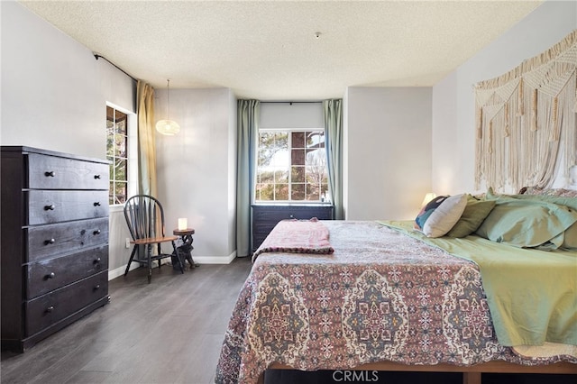 bedroom featuring a textured ceiling, baseboards, and wood finished floors