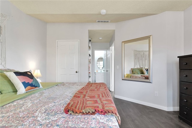 bedroom with dark wood-style floors, baseboards, visible vents, and a textured ceiling