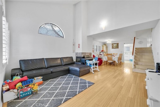 living area with stairs, a high ceiling, and wood finished floors