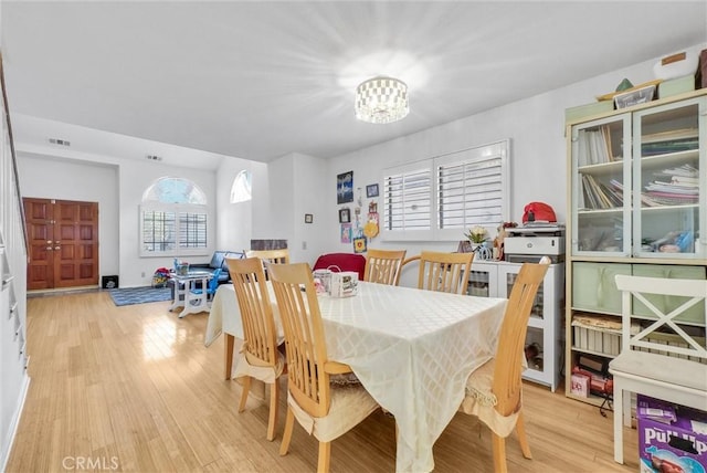 dining space with an inviting chandelier, visible vents, and light wood-style floors