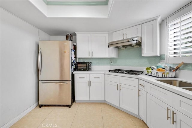 kitchen with appliances with stainless steel finishes, white cabinets, light countertops, and under cabinet range hood