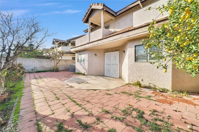 rear view of property featuring stucco siding, fence, cooling unit, and a patio