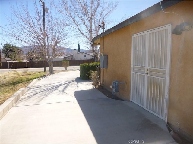 view of side of home with a patio area, fence, and stucco siding