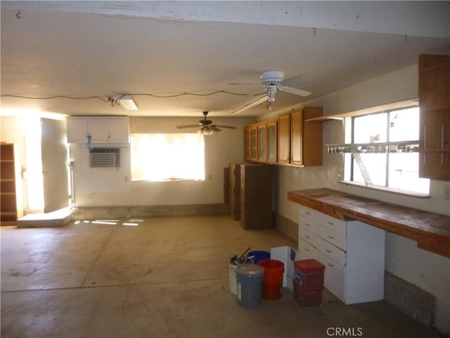 kitchen featuring concrete flooring, a wall mounted AC, and white cabinetry