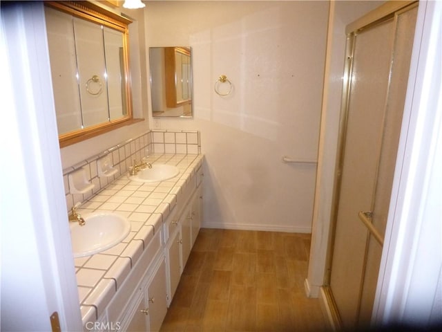 full bath with double vanity, tasteful backsplash, a sink, and wood finished floors