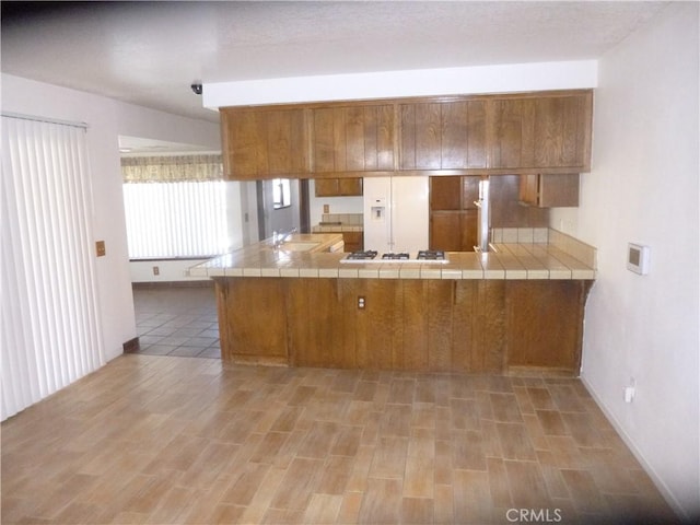 kitchen featuring white appliances, tile counters, and brown cabinets