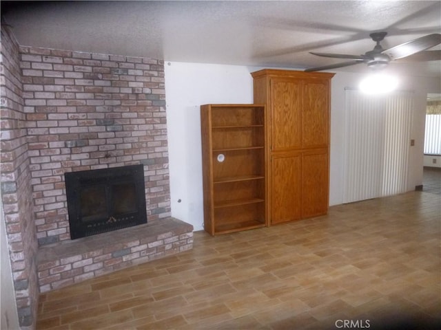 unfurnished living room with ceiling fan, a fireplace, and light wood-style flooring