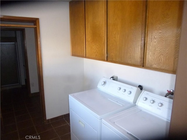 clothes washing area featuring dark tile patterned flooring, cabinet space, and washer and dryer