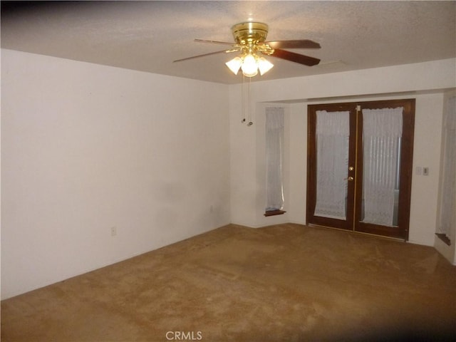 carpeted spare room featuring ceiling fan and french doors