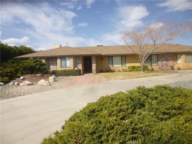 ranch-style home featuring concrete driveway and brick siding