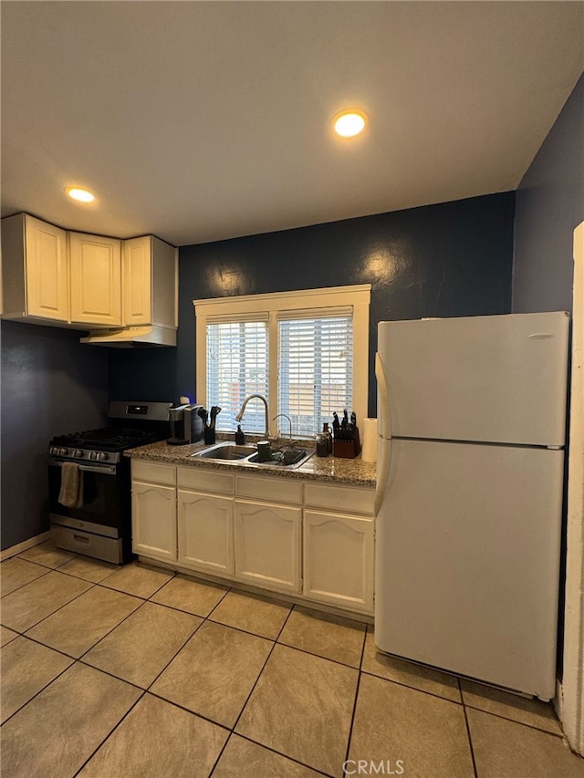 1375 E 46th St, Los Angeles, CA 90011 - kitchen featuring freestanding refrigerator, stainless steel range with gas stovetop, light tile patterned floors, white cabinetry, and a sink