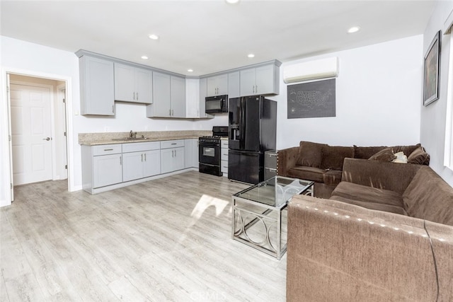 living area featuring light wood finished floors, a wall unit AC, and recessed lighting