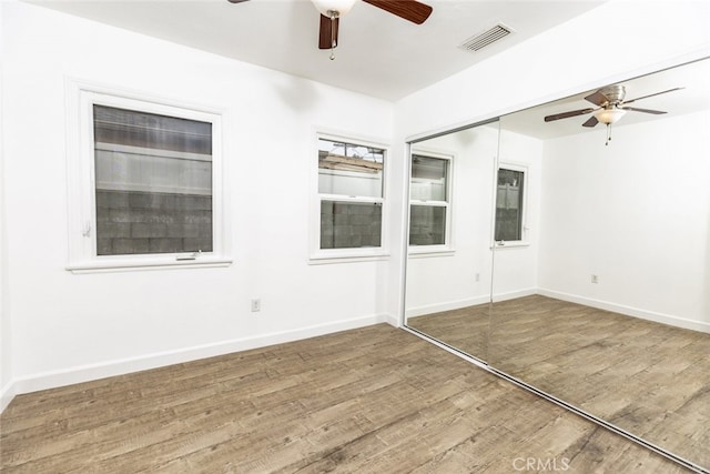 empty room with visible vents, ceiling fan, baseboards, and wood finished floors