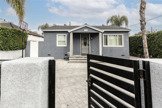 bungalow featuring roof with shingles, crawl space, a fenced front yard, and stucco siding