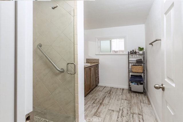 bathroom with wood finished floors, a shower stall, vanity, and baseboards