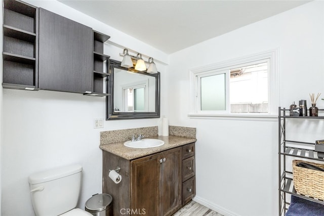 bathroom with toilet, baseboards, and vanity