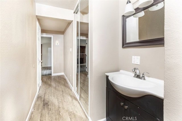 bathroom featuring baseboards, wood finished floors, and vanity