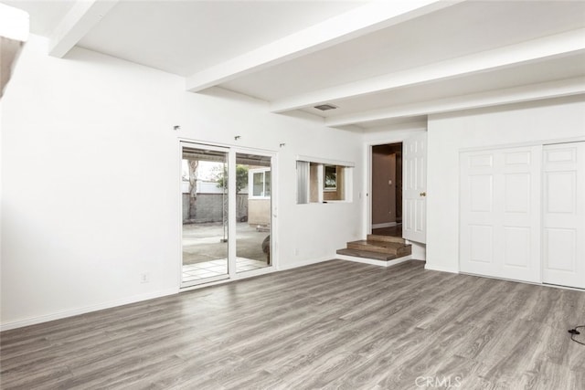 interior space with visible vents, beamed ceiling, baseboards, and wood finished floors