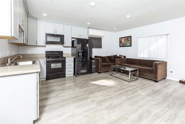 kitchen featuring a sink, open floor plan, an AC wall unit, light countertops, and black appliances