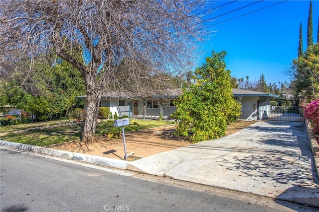 view of front of property featuring a gate, concrete driveway, and stucco siding