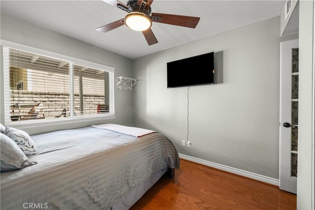 bedroom featuring ceiling fan, baseboards, and wood finished floors