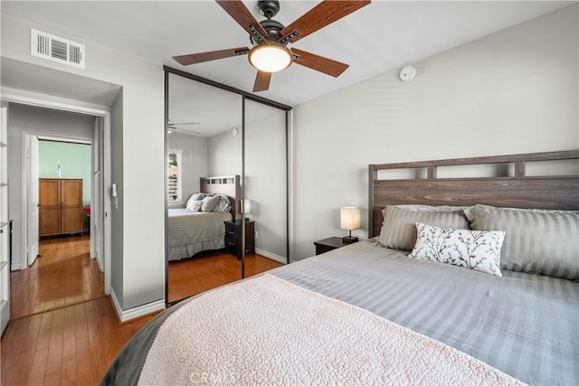 bedroom featuring a closet, visible vents, wood-type flooring, a ceiling fan, and baseboards