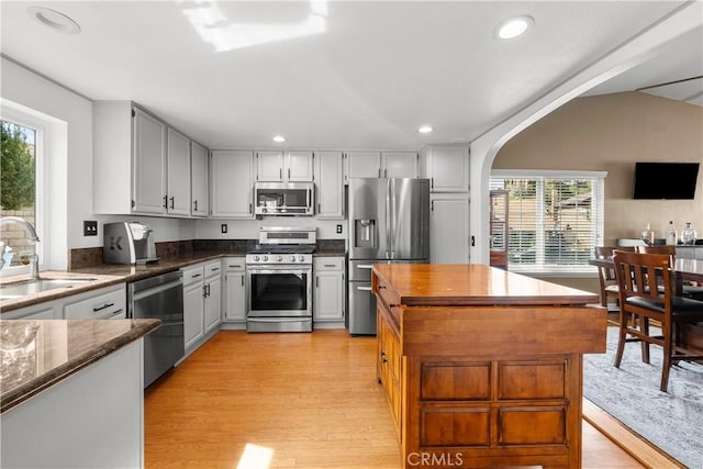 kitchen with arched walkways, light wood-style flooring, recessed lighting, stainless steel appliances, and a sink