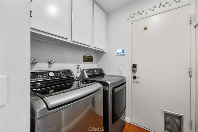 laundry area featuring independent washer and dryer, wood finished floors, and cabinet space