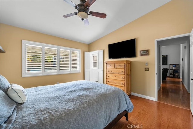 bedroom with lofted ceiling, a ceiling fan, baseboards, and wood finished floors