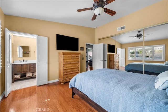 bedroom with ensuite bathroom, a sink, visible vents, a closet, and light wood finished floors