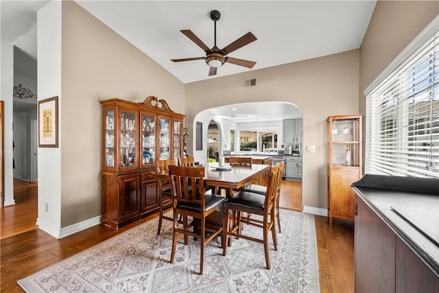 dining space with arched walkways, hardwood / wood-style flooring, visible vents, and a healthy amount of sunlight