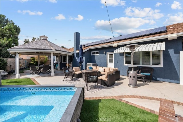 back of house with a fenced in pool, solar panels, stucco siding, an outdoor hangout area, and a patio area