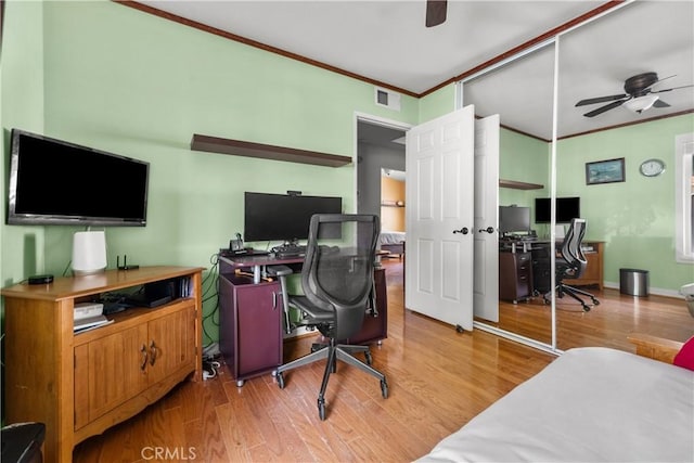 office space featuring visible vents, baseboards, ceiling fan, crown molding, and light wood-style floors