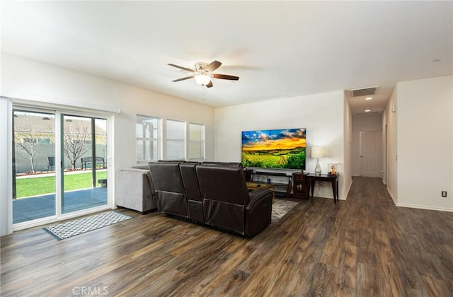 living area featuring baseboards, dark wood-type flooring, visible vents, and a ceiling fan