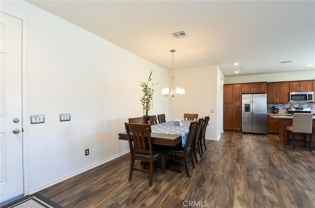 dining space featuring dark wood-style floors, a notable chandelier, visible vents, and baseboards