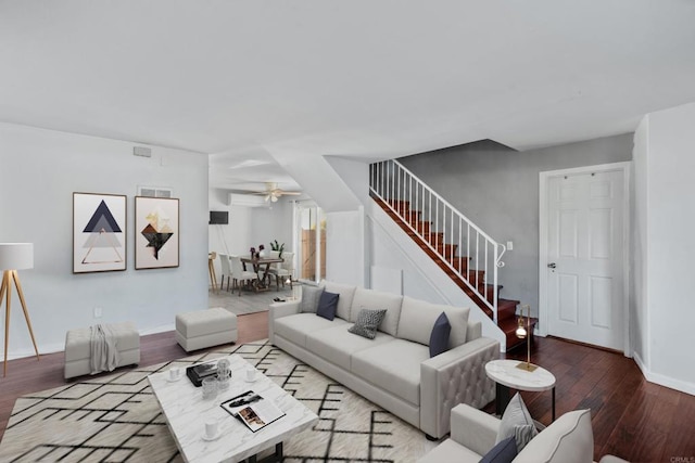 living area with baseboards, a ceiling fan, wood finished floors, stairs, and an AC wall unit